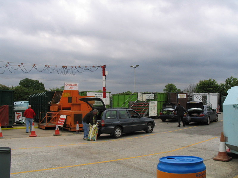 Cars and people at a recycling centre.