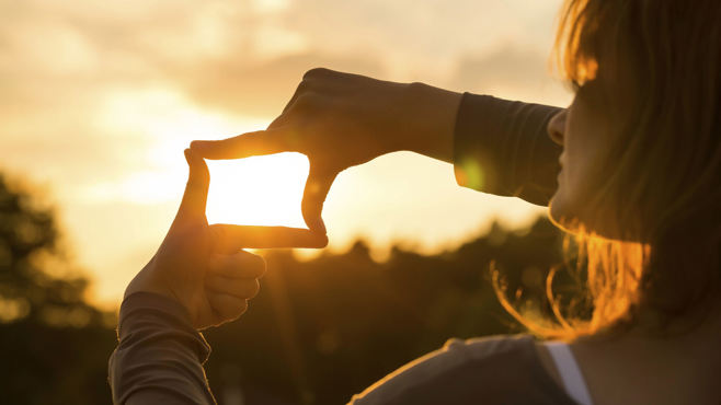 Lady using hands to frame the sun