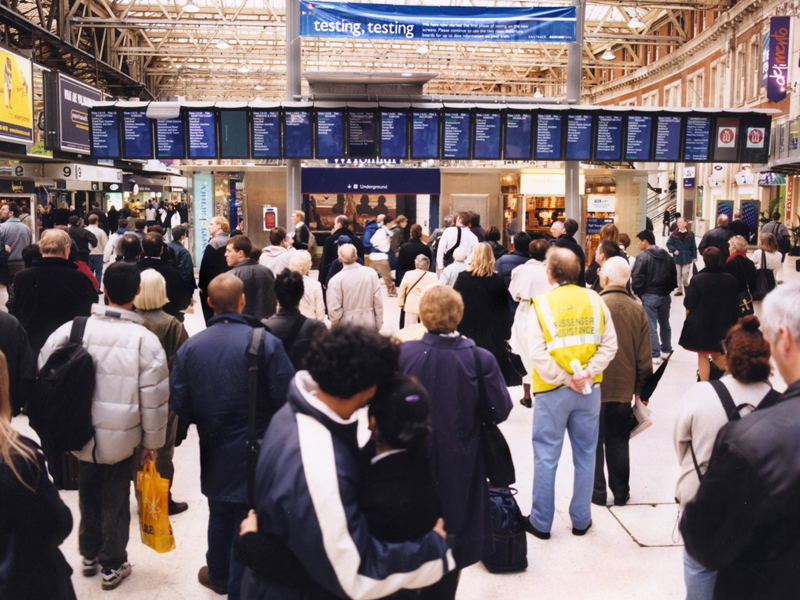 a crowed rail station of people looking at the departure boards.