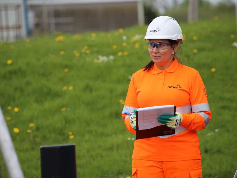 Woman in PPE holding a clipboard.
