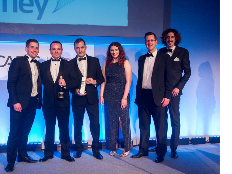 A group of Amey employees, in formal attire, holding an award.