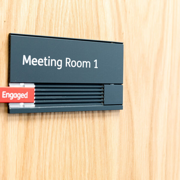 Image of a meeting room, with an 'engaged' sign on the door.