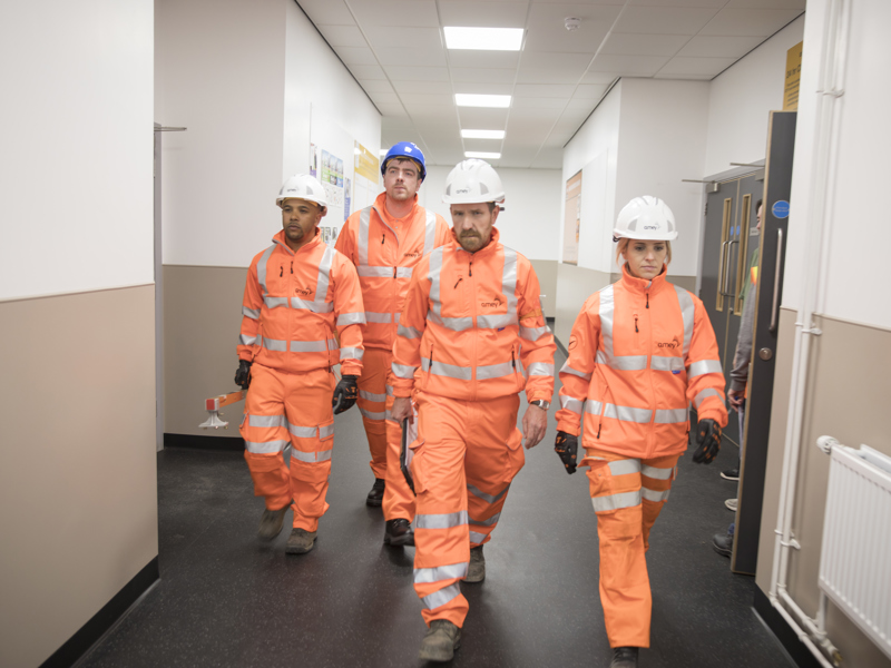 Four Amey employees in PPE, walking down a corridor.