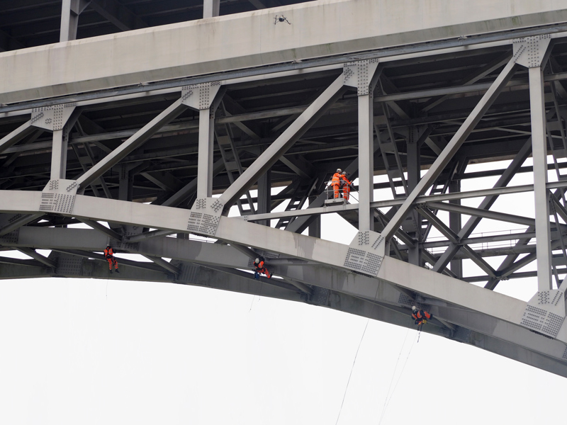 Two men in safety equipment carrying out a bridge inspection.