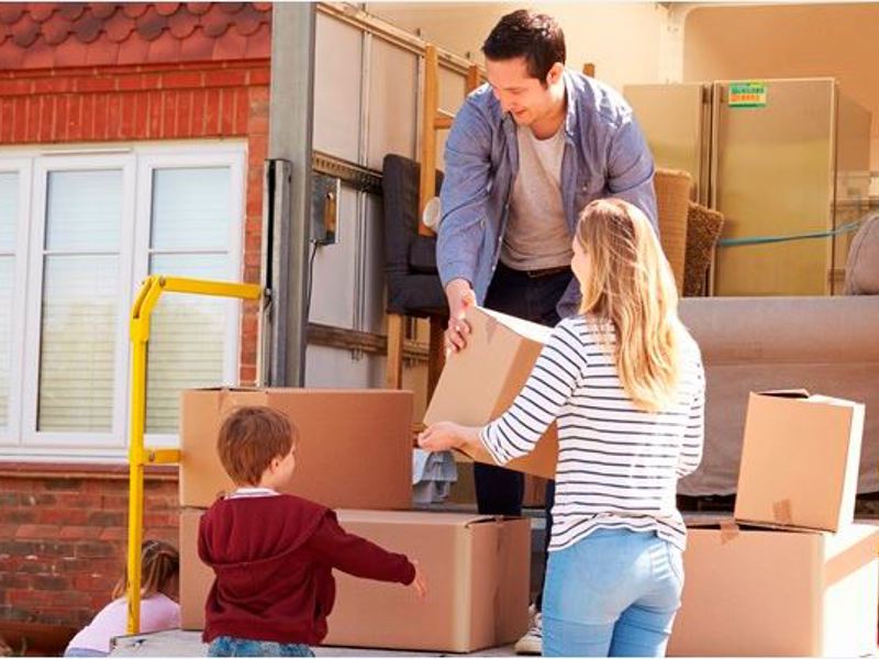 a family moving boxes from a removals vehicle. 