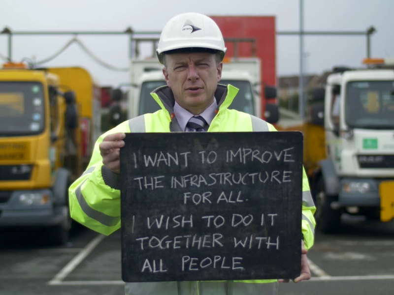 A man in PPE holding a sign.