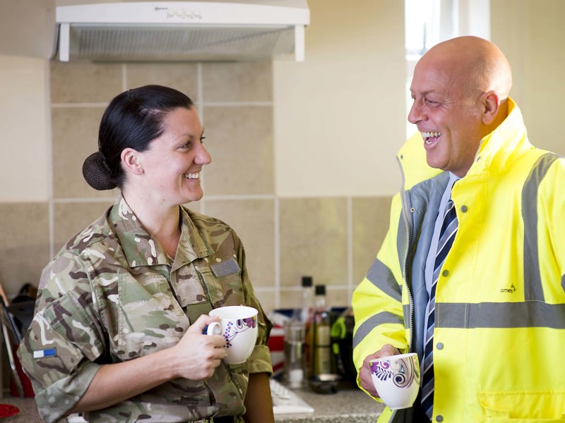 Military personnel and Amey employee having a coffee.
