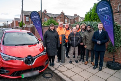 Residents standing around EV charger and car 