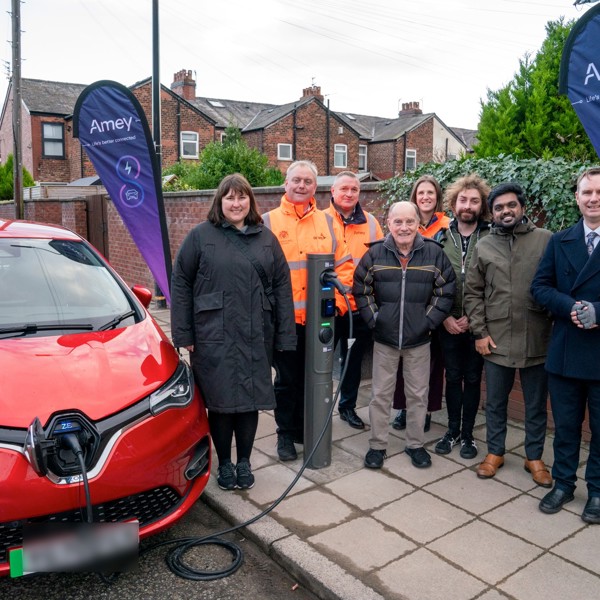 Residents standing around EV charger and car 