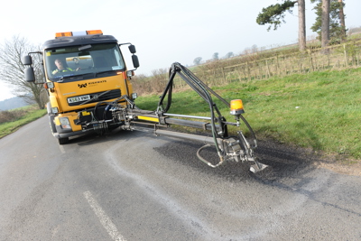 Image of a pothole being repaired using machinery.