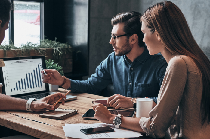 Image of three people looking at data on a laptop
