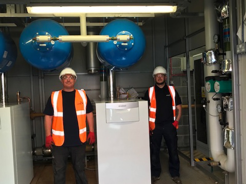 Two Amey employees in PPE, stood in a control room.