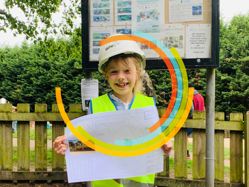 Child holding a picture in front of a playpark. 
