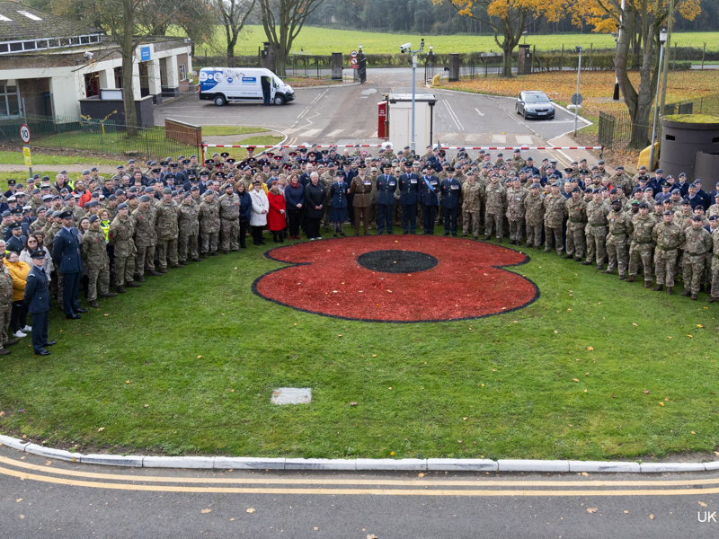 Ariel image of Military personal stood around a poppy painted on the grass