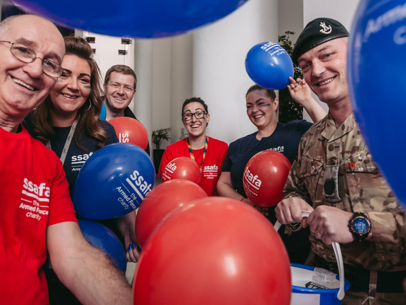 Group of people holding red and blue SSAFA balloons.