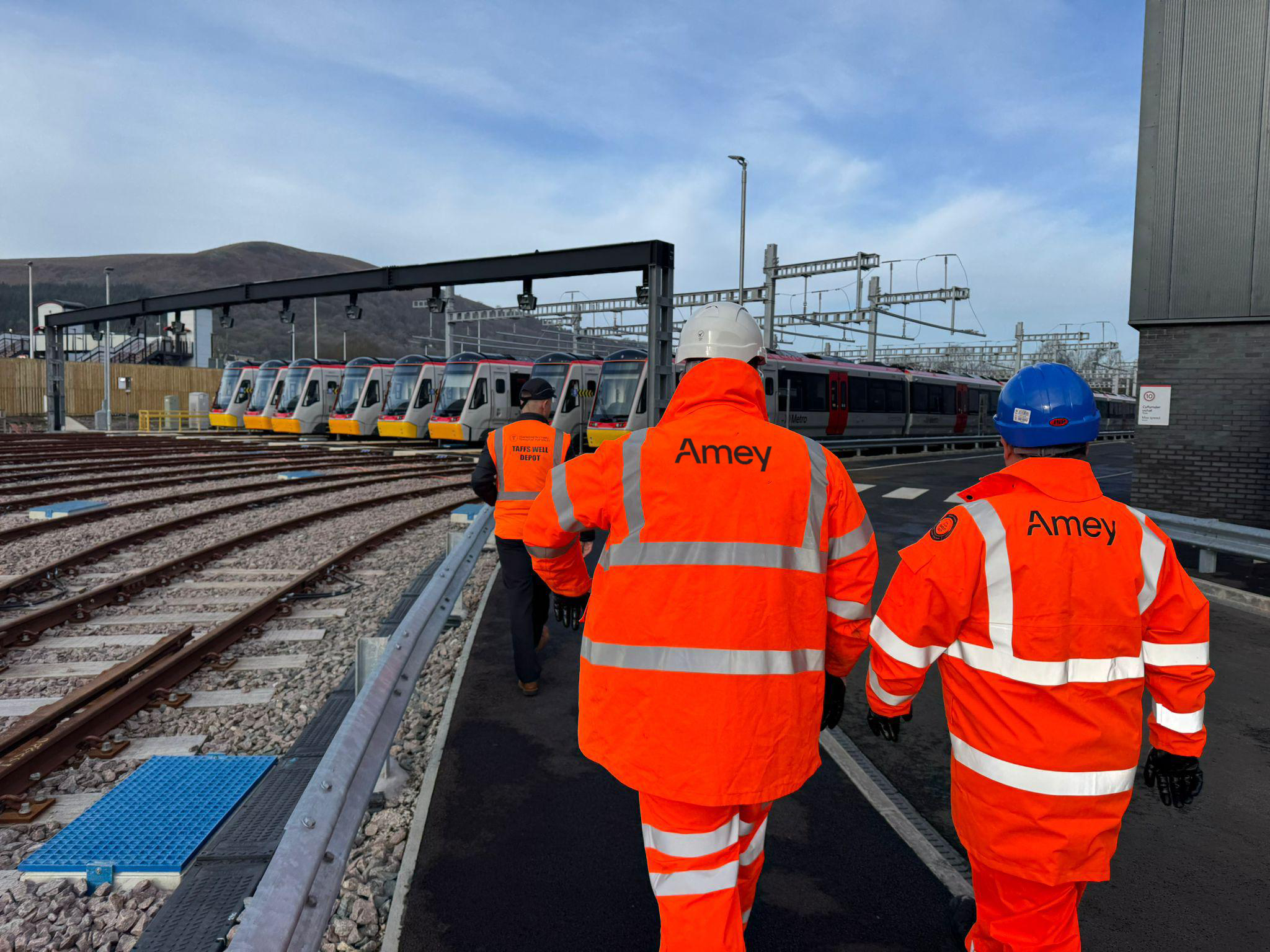 two men in PPE, on a rail track