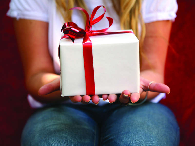 Image of a girl holding a white present, with a red bow.