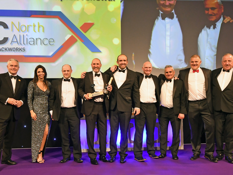 A group of Amey employees, in formal attire, holding an award.