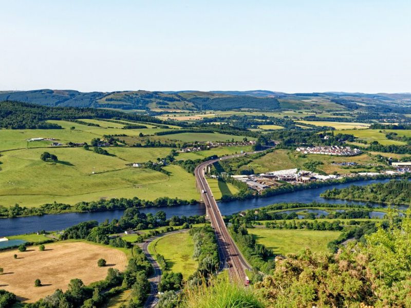 Ariel view of a bridge over a river surrounded by fields.