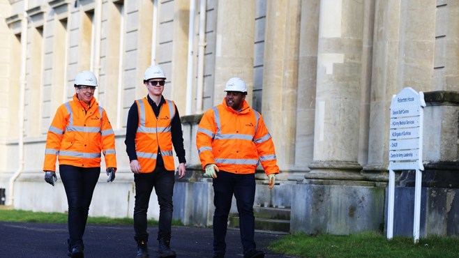 Three Amey, male employees in PPE in front of a building