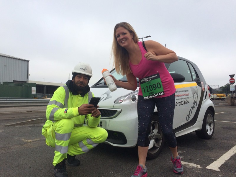 Image of an Amey employee in PPE, with a runner in the Birmingham run.