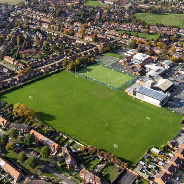 Aerial view of a secondary school campus with sports fields and surrounding residential housing.